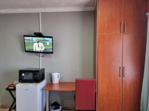 Zimmer mit einem Tisch und einem TV an der Wand in der Unterkunft Monate BNB in Kuruman