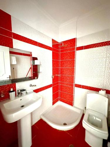 a red and white bathroom with a sink and a toilet at Albania Dream Apartment 31 in Metogjashta