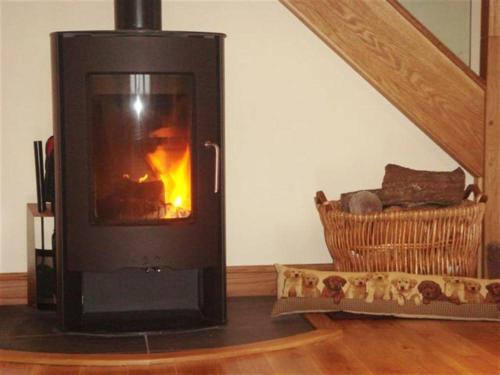 a wood stove with a fire in a room at Criffel Glen in Dumfries