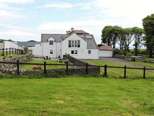 a white house with a fence in a field at Criffel Glen in Dumfries