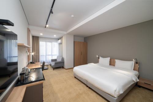 a hotel room with a large white bed and a desk at Ambassador Orient in Bishkek