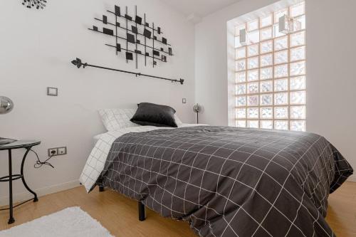 a bedroom with a bed with a gray blanket and a window at Apartment Delicias by SharingCO in Madrid