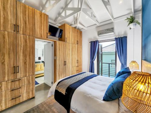 a bedroom with wooden cabinets and a bed with blue pillows at Virginia Avenue Villas - Adriatica and Botanica in Cape Town