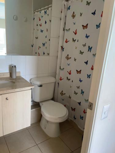 a bathroom with a toilet and a shower curtain with butterflies at Papudo Laguna Un Lugar Privilegiado in Papudo