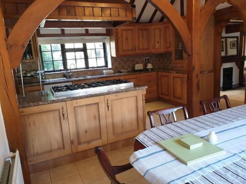 a kitchen with wooden cabinets and a table with a table sidx sidx sidx at Beautiful thatched cottages in Brentwood. in Kelvedon Hatch