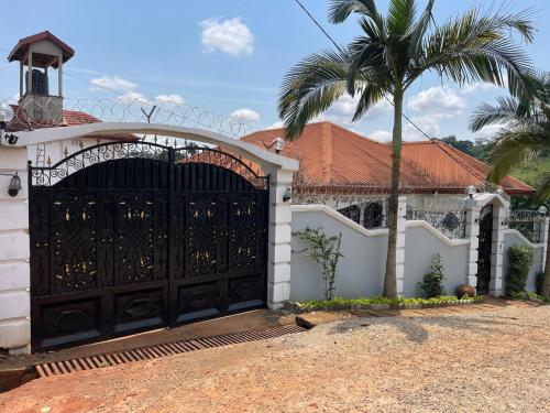 a house with a black gate and a palm tree at PEACE GUEST HOUSE in Yaoundé