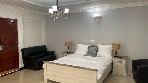 a bedroom with a bed and a black chair at PEACE GUEST HOUSE in Yaoundé