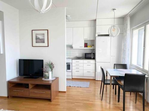 PASILA Modern flat centrally located في هلسنكي: مطبخ وغرفة طعام مع طاولة وتلفزيون