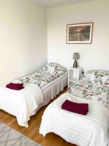 two beds in a room with white walls at PASILA Modern flat centrally located in Helsinki