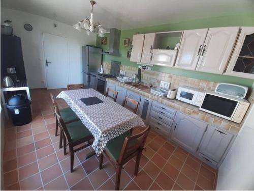 a kitchen with a table and chairs and a kitchen with white cabinets at Maison confort et repos in Crecy la Chapelle