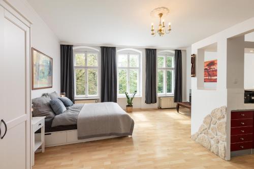 ein weißes Schlafzimmer mit einem Bett und Fenstern in der Unterkunft Apartments am Fernsehturm in Berlin