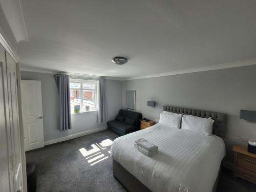 a bedroom with a large white bed and a chair at The Beeches Hotel & Leisure Club in Nottingham
