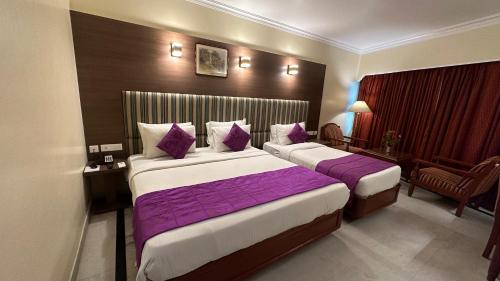 two beds in a hotel room with purple sheets at Hotel Annamalai International in Puducherry