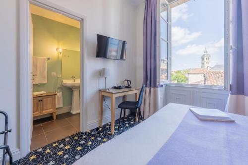 um quarto de hotel com uma cama, uma secretária e uma janela em Hotel Heritage em Cognac