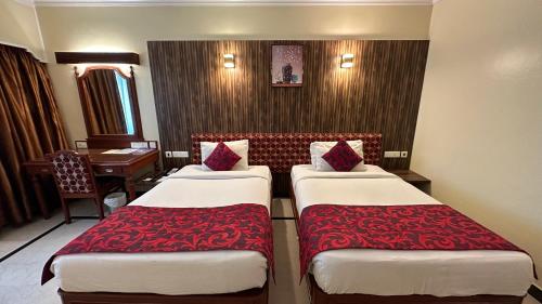 a hotel room with two beds and a desk at Hotel Annamalai International in Puducherry