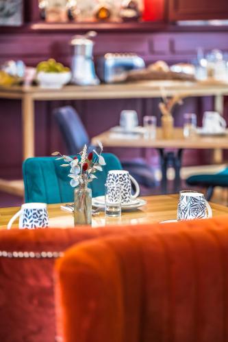 een houten tafel met een vaas met bloemen erop bij Hotel Heritage in Cognac