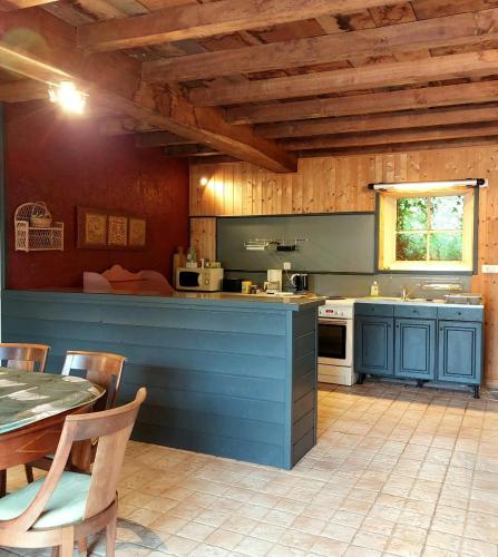 een keuken met blauwe kasten en een tafel in een kamer bij Moulin de Frely in Pouzauges