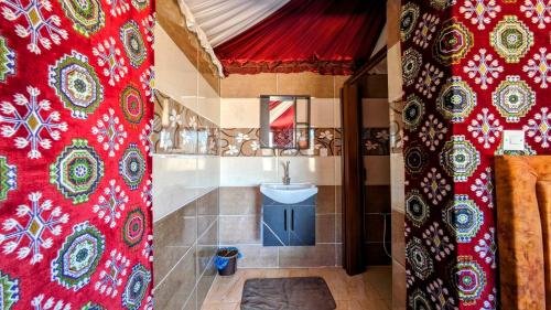 a bathroom with a sink and a red shower curtain at WhyDesert Camp & Tours in Wadi Rum