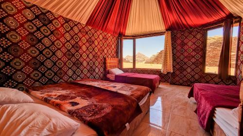 1 dormitorio con 2 camas en una habitación con paredes rojas en WhyDesert Camp & Tours, en Wadi Rum