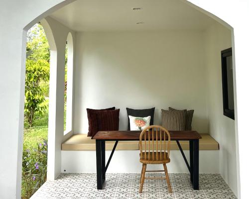 - une table avec des oreillers et une chaise à côté d'une fenêtre dans l'établissement Tubtao Sleepy Hill, à Pong Talong