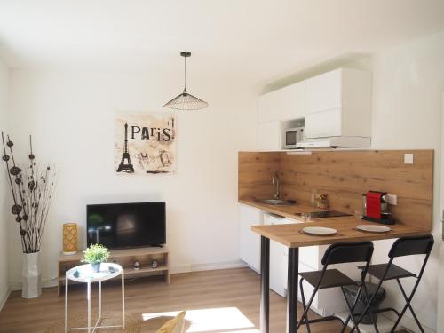 une cuisine avec une table et des chaises dans une pièce dans l'établissement Terrasse, vue sur jardin arboré et place de parking, à Rennes
