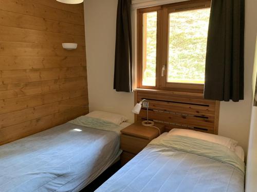 two twin beds in a room with a window at Paradiski pied des pistes plan peisey in Peisey-Nancroix