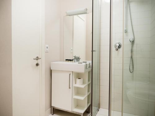 uma casa de banho branca com um lavatório e um chuveiro em Lake Drive Rooms&Apartments em Tirana