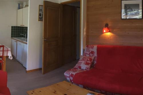 un salon avec un canapé rouge et une cuisine dans l'établissement Paradiski pied des pistes vallandry, à Landry