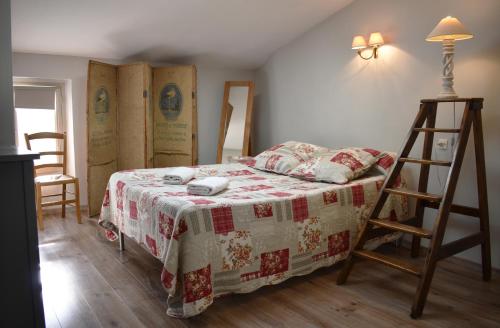 - une chambre avec un lit avec une couverture et une échelle dans l'établissement Chez Elia, pour les amoureux des vieilles pierres, à Cesseras