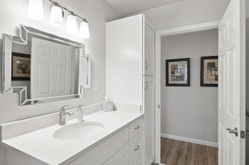 a white bathroom with a sink and a mirror at Palm Paradise Waterfront Home - Flagler Beach - Dock - Pet Friendly - Close To The Beach in Flagler Beach