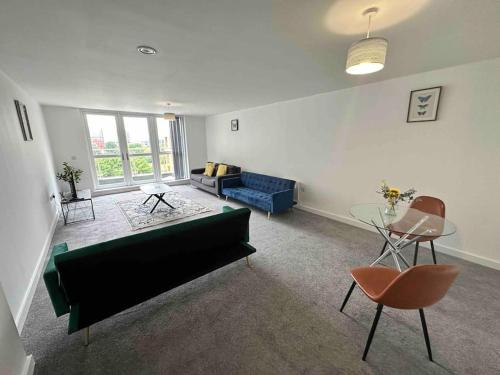 a living room with a green couch and a table at XL 2 Bed Central MCR Apt Sleeps 7 in Manchester