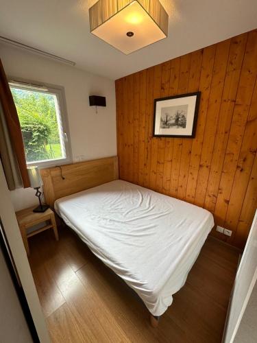 - une chambre avec un lit blanc dans un mur en bois dans l'établissement Appartement T3 avec jardin et piscine - Luz Saint Sauveur, Val de Roland, à Luz-Saint-Sauveur