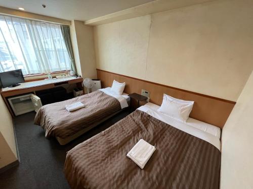 a hotel room with two beds and a television at Hotel Axia Inn Kushiro in Kushiro