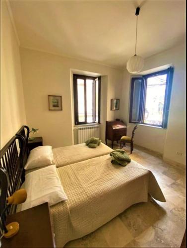 a bedroom with two beds and a desk and windows at Casa Vittorio Emanuele in Fiuggi
