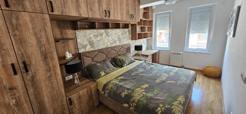 a bedroom with a bed with a wooden wall at Kraljevački Lux parking GARAŽA in Kraljevo