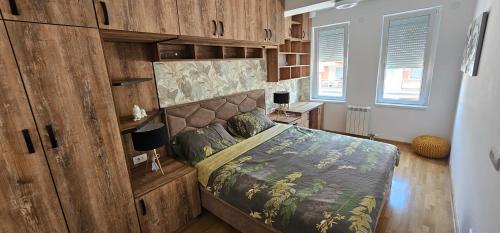 ein Schlafzimmer mit einem Bett mit einer Holzwand in der Unterkunft Kraljevački Lux parking GARAŽA in Kraljevo