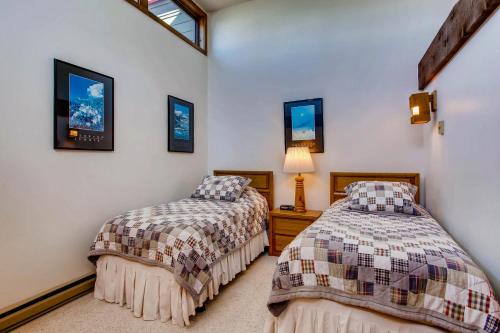 two beds in a room with white walls at The Plaza Condominiums by Crested Butte Mountain Resort in Mount Crested Butte