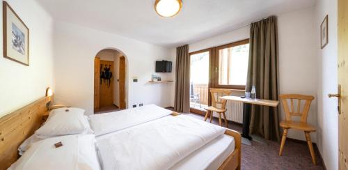 a hotel room with a bed and a desk and a window at Berghotel Schlemmer in Bressanone