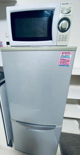 a microwave sitting on top of a refrigerator at STAR YONEGAHAMA l 米が浜通 in Kusugaurachō