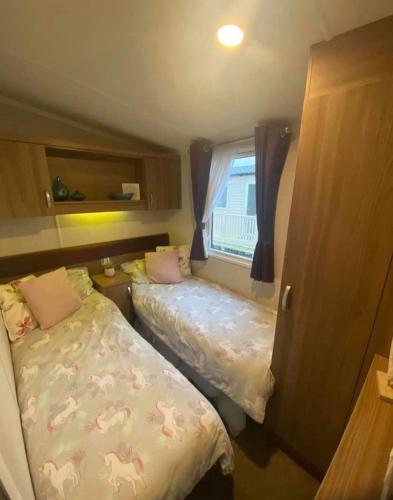 a small bedroom with two beds and a window at Tenby - Kiln Park caravan hire in Pembrokeshire