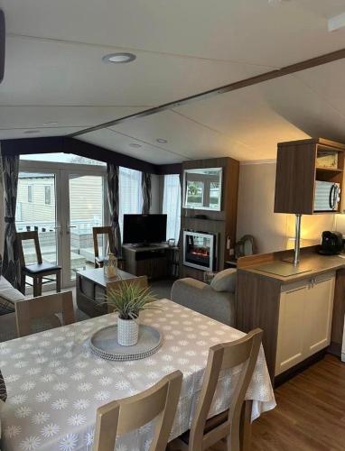 ein Wohnzimmer mit einem Tisch und ein Wohnzimmer mit einem Sofa in der Unterkunft Tenby - Kiln Park caravan hire in Pembrokeshire