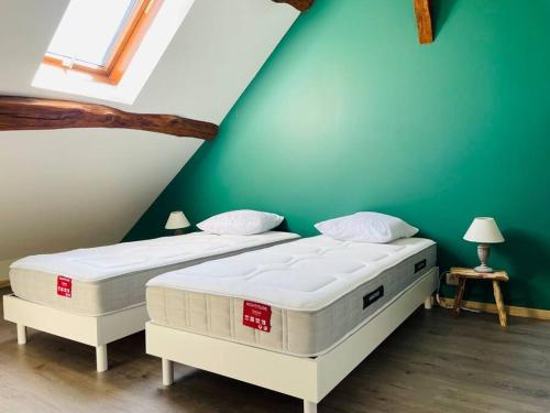 2 camas en una habitación con una pared verde en Le Gîte des Hautes Côtes, en Nolay