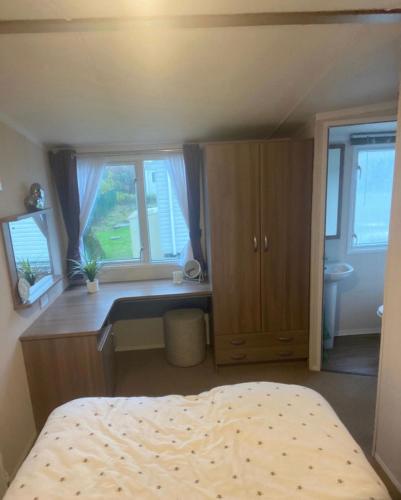 Schlafzimmer mit einem Bett, einem Schreibtisch und Fenstern in der Unterkunft Tenby - Kiln Park caravan hire in Pembrokeshire