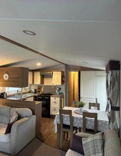 Tenby - Kiln Park caravan hire في بيمبروكشاير: مطبخ وغرفة معيشة مع طاولة وكراسي