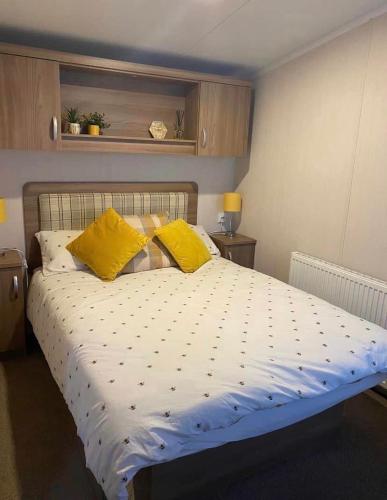 um quarto com uma cama grande e almofadas amarelas em Tenby - Kiln Park caravan hire em Pembrokeshire