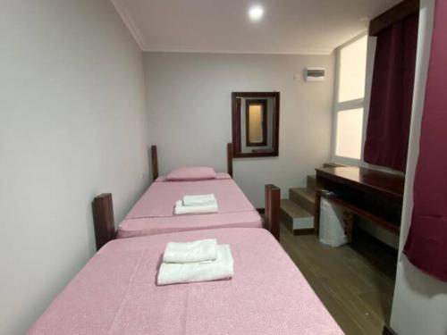 two beds in a room with pink sheets and a piano at Sliema - Double Room in Sliema