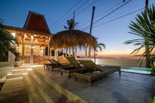 un patio con tumbonas y vistas al océano en Sunset House Ceningan, 10 person beachfront private villa, en Nusa Lembongan