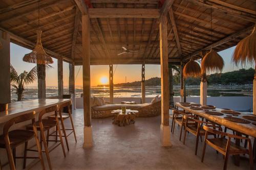 ein Restaurant mit Tischen und Stühlen und Sonnenuntergang in der Unterkunft Sunset House Ceningan, 10 person beachfront private villa in Nusa Lembongan