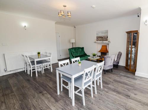 a living room with tables and chairs and a couch at Woodford Hotel in London