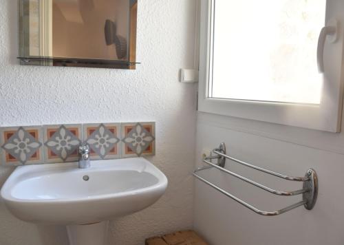 La salle de bains est pourvue d'un lavabo blanc et d'une fenêtre. dans l'établissement Chez Elia, pour les amoureux des vieilles pierres, à Cesseras